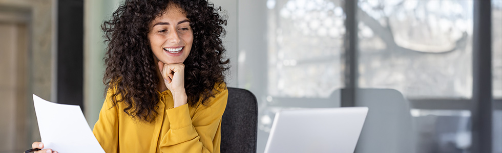 A woman sits in an empty office looking at a legal document and her laptop
